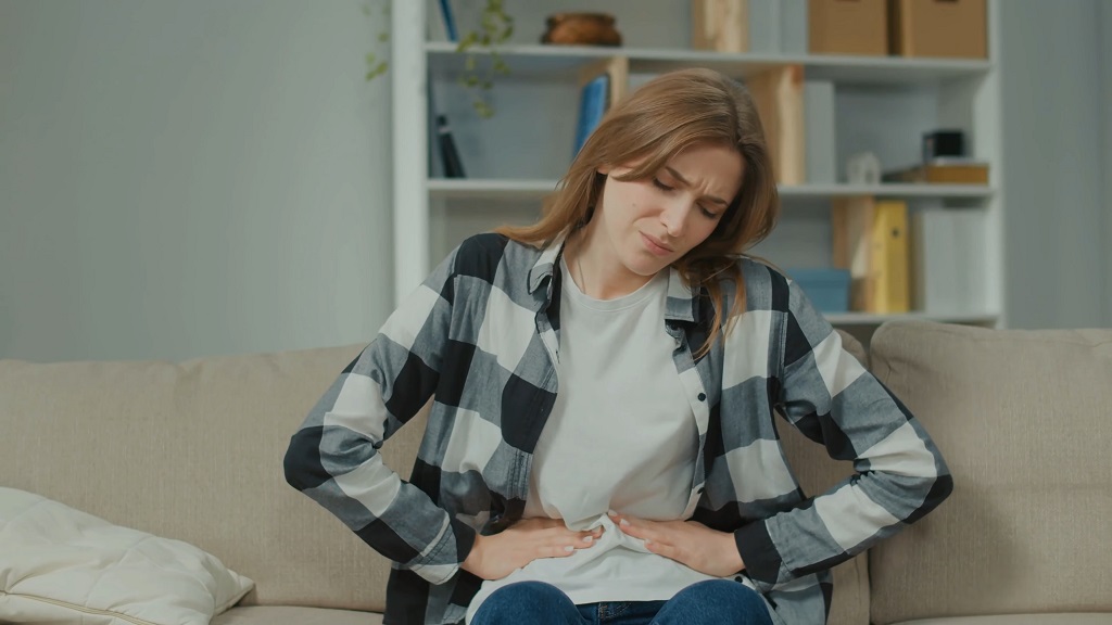 The woman is holding her stomach due to pain