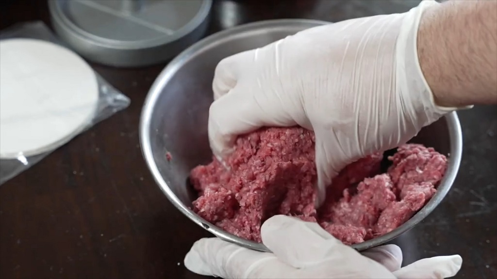 Mixing ground meat with gloves on the hands