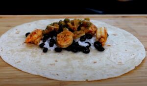 Shrimp, rice, and black beans are nestled within a warm tortilla